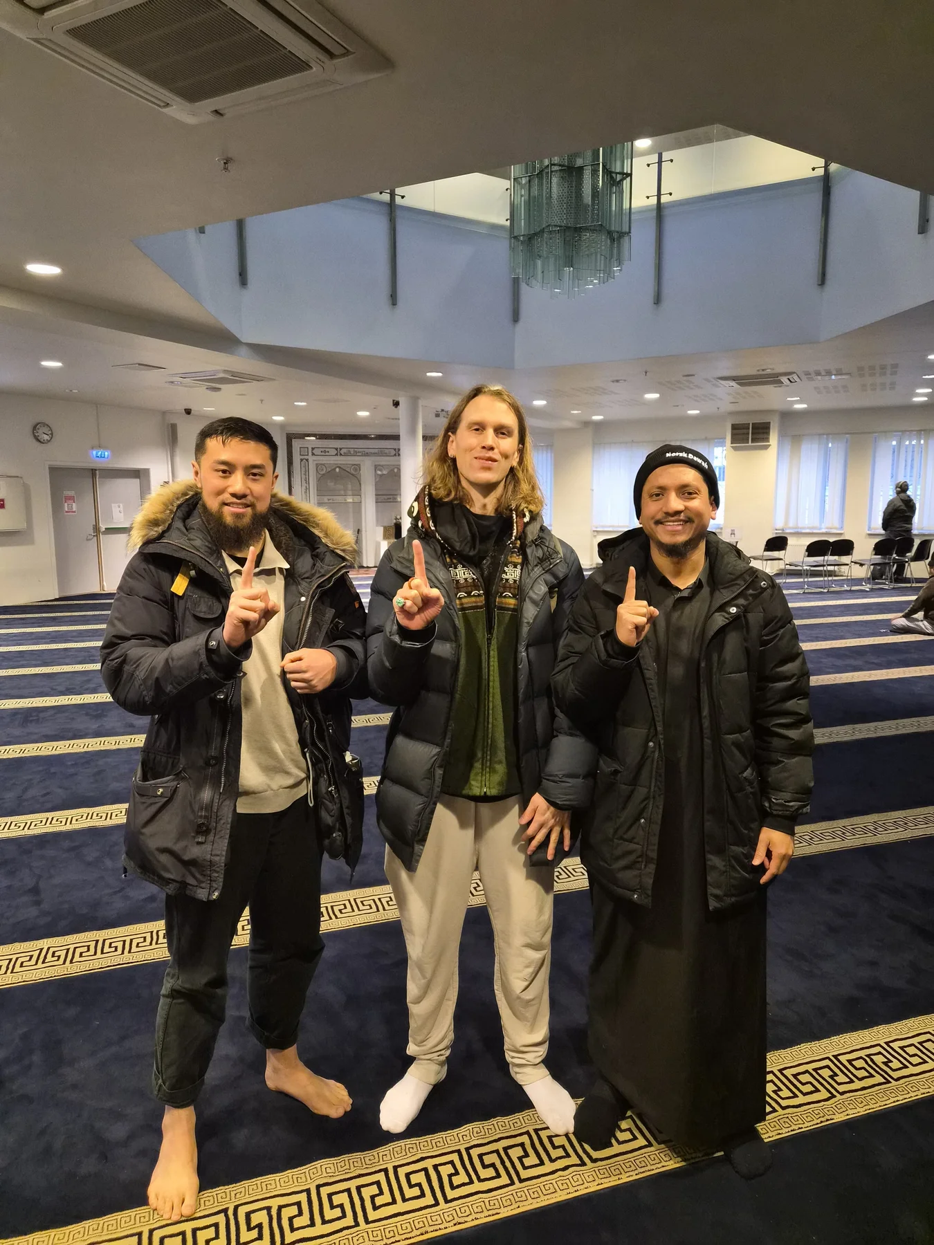 Three people standing together inside a prayer hall