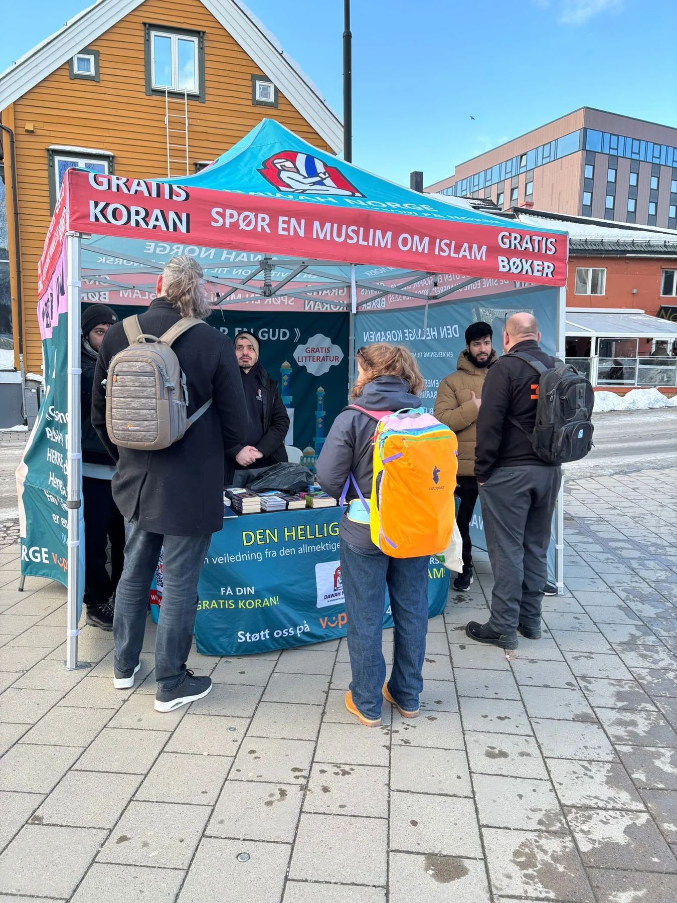People with backpacks talking at a Dawah Norway information tent in Tromsø