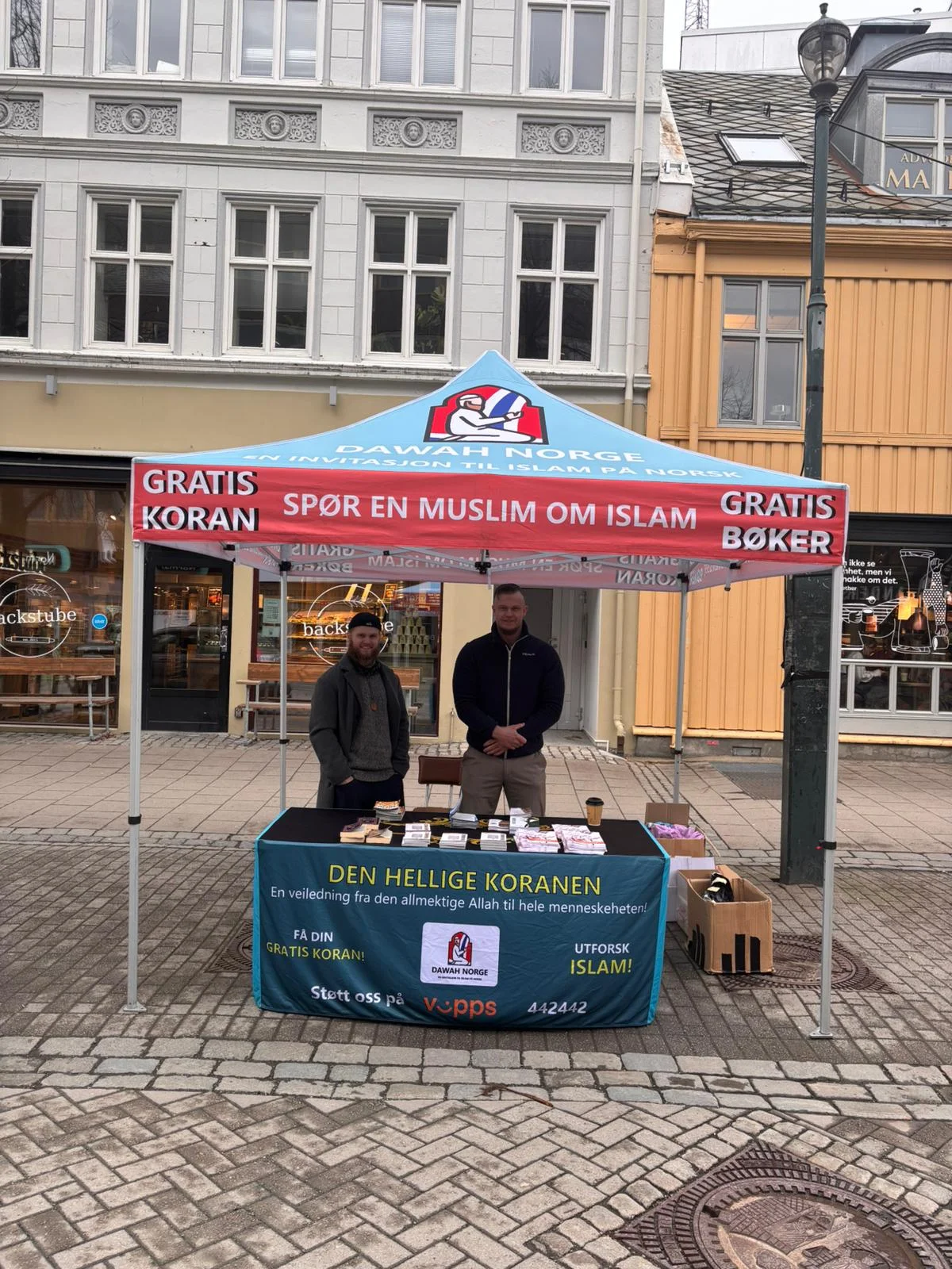 Two people behind a table of books at a Dawah Norway stand in Trondheim